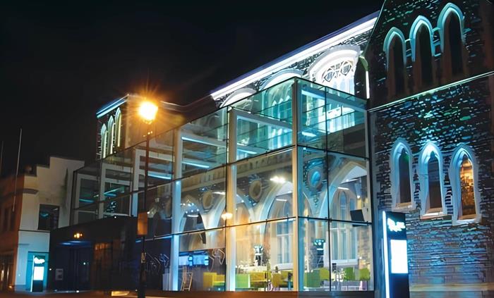 External street view at night time image of the Gwyn Hall. Highlighting the cafe area in the glass atrium